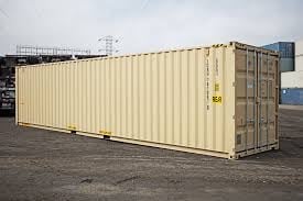 Beige shipping container on outdoor lot with industrial setting and cranes in background