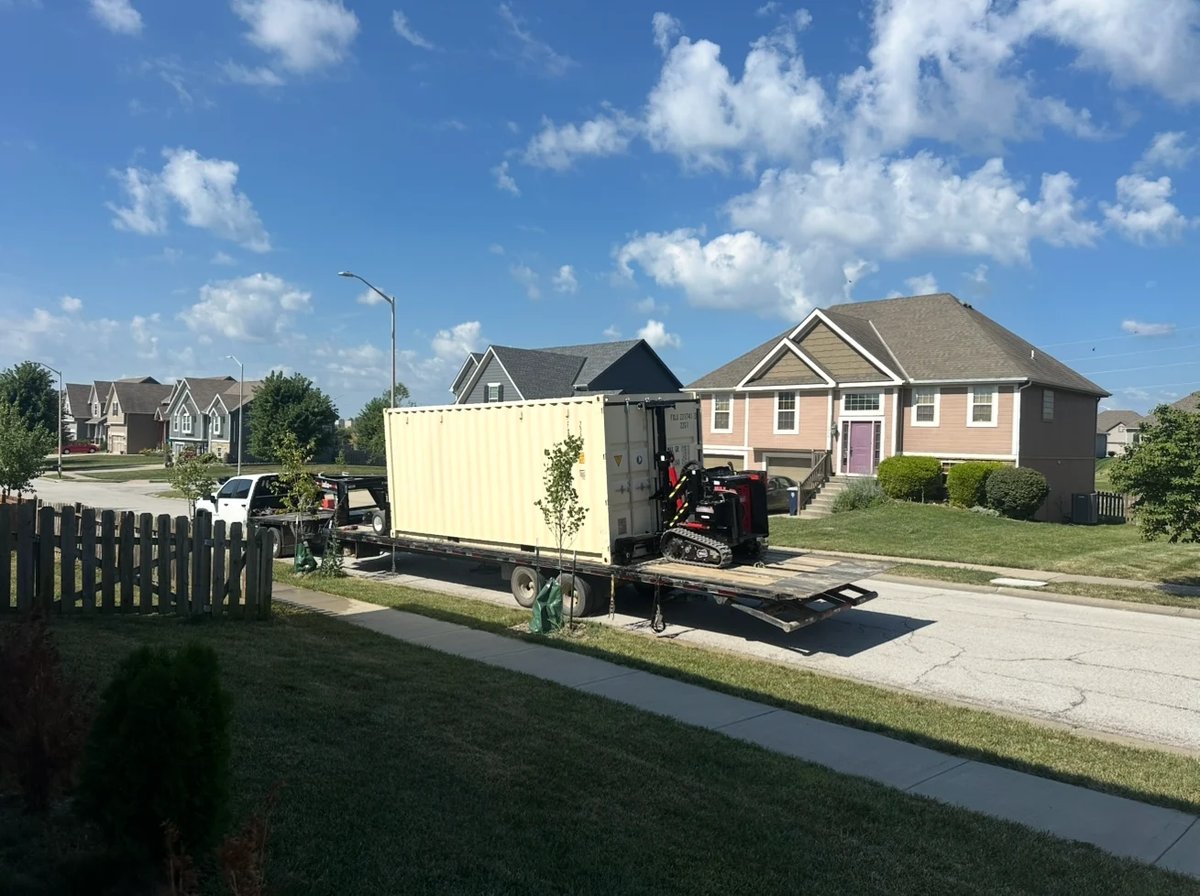Moving truck parked in driveway of residential home on sunny suburban street