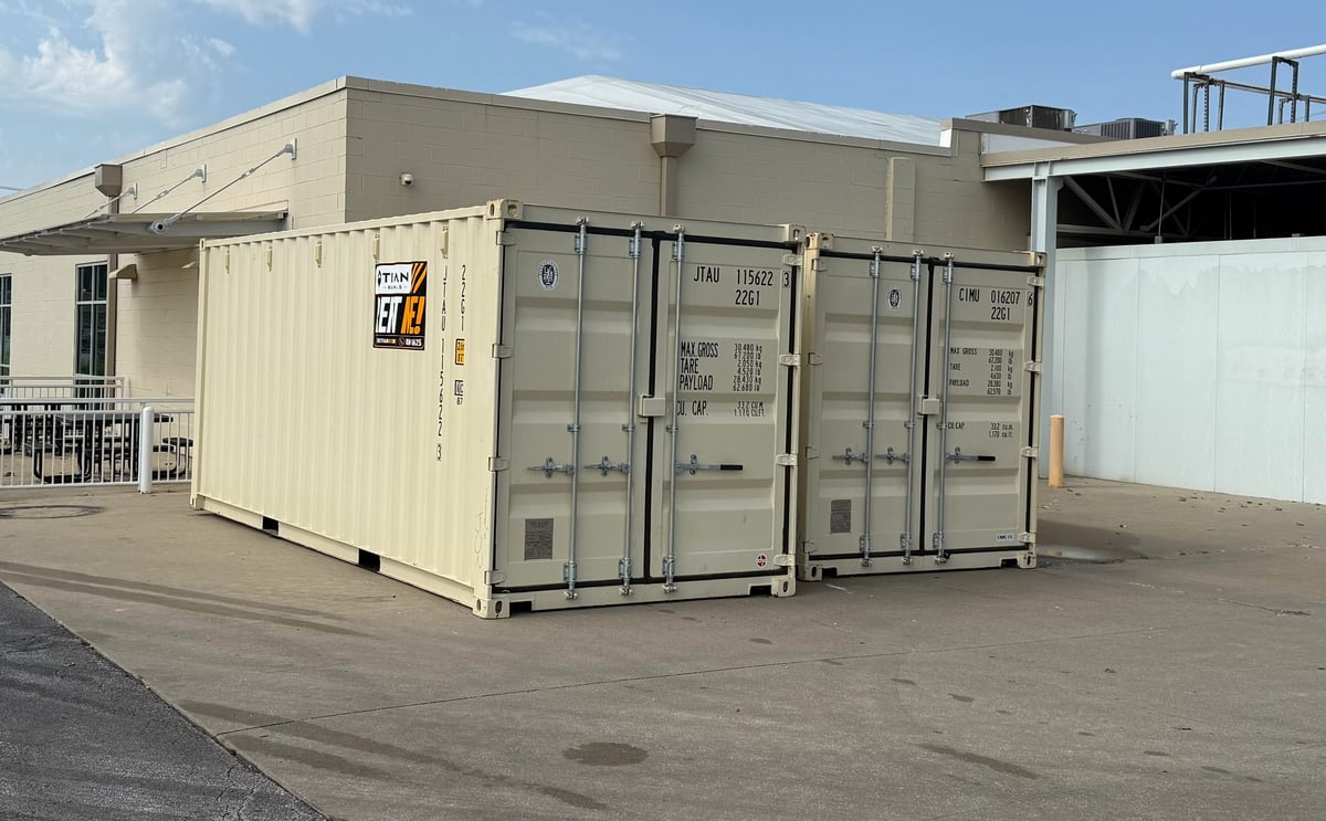 Industrial shipping containers and prefabricated metal structures in a warehouse yard under clear blue sky