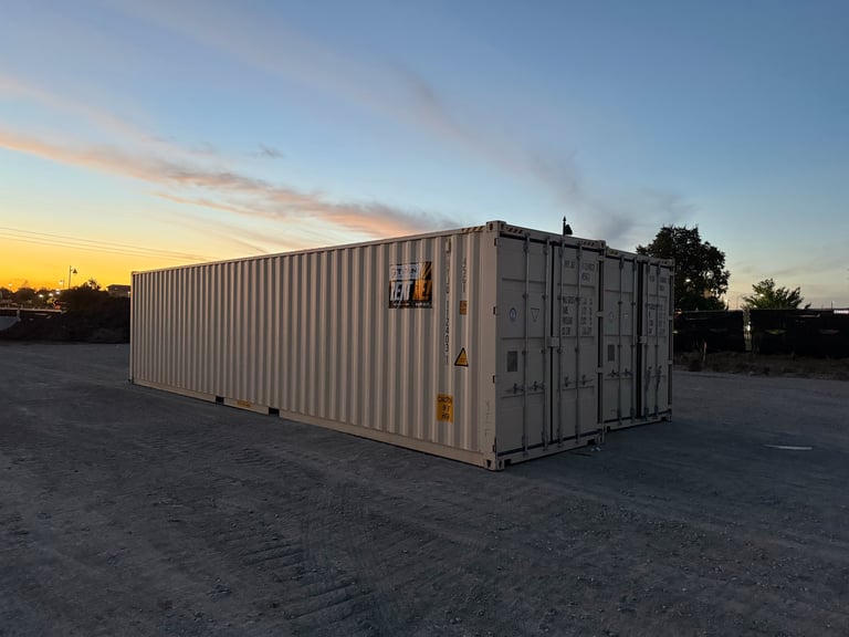 Large white shipping container in an industrial yard at sunset with trees in the background