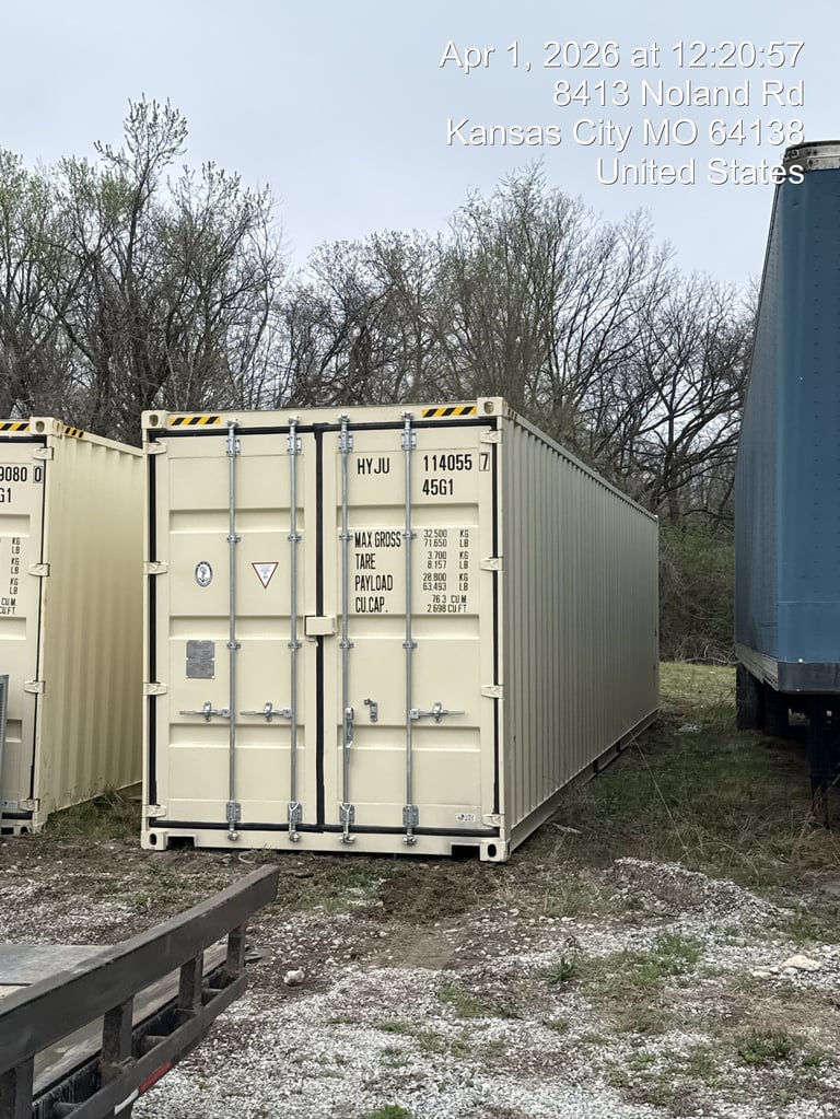 Beige shipping container with yellow and black hazard stripes on doors in an outdoor industrial lot